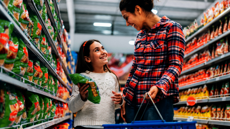 Eine Mutter und ihre Tochter lächeln sich im Supermarkt zu